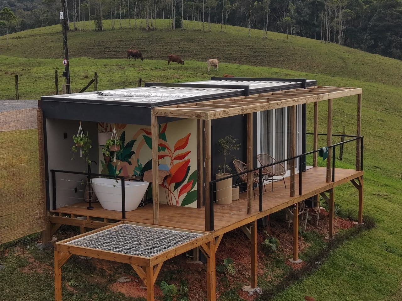 Deck de madeira da Cabana Box com guarda-corpo metálico e vista para o vale