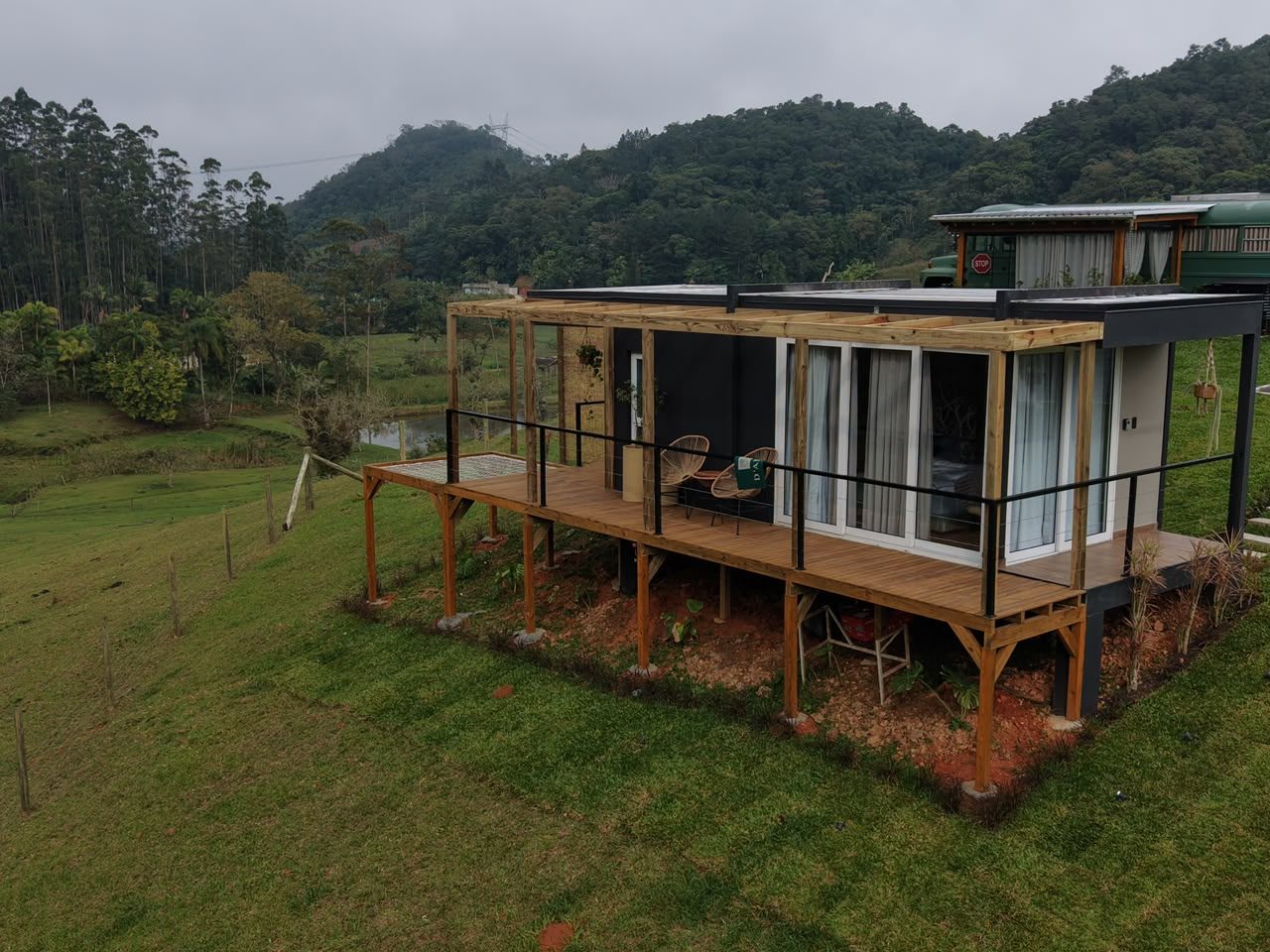 Vista aérea da Cabana Box com pergolado, banheira de imersão no deck e painel artístico de folhagens