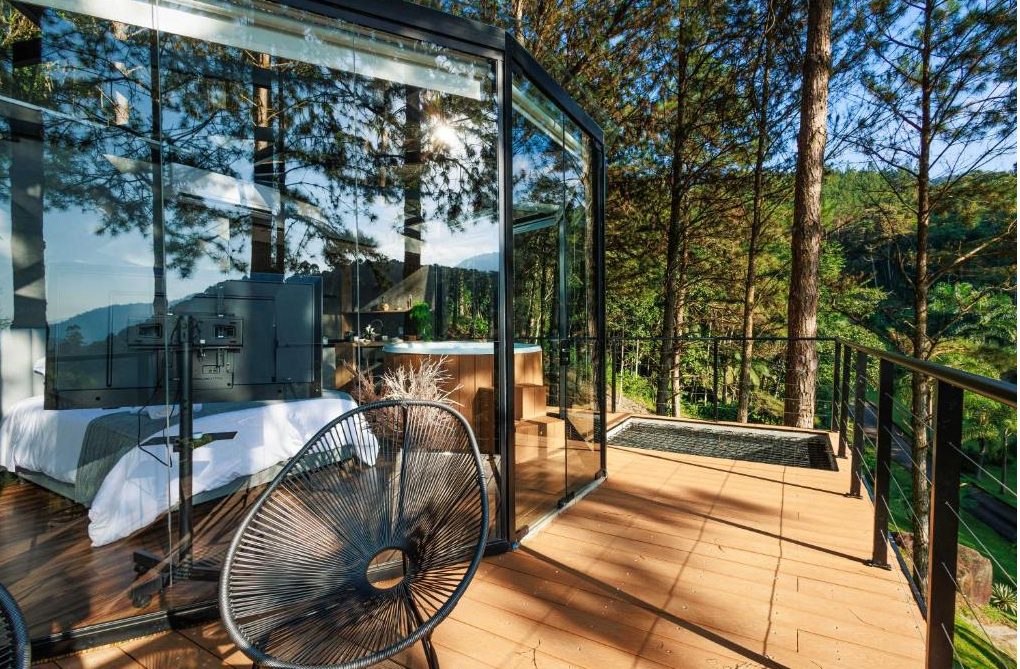 Deck externo da Cabana Cristallo com poltrona, guarda-corpo metálico e vista para a mata