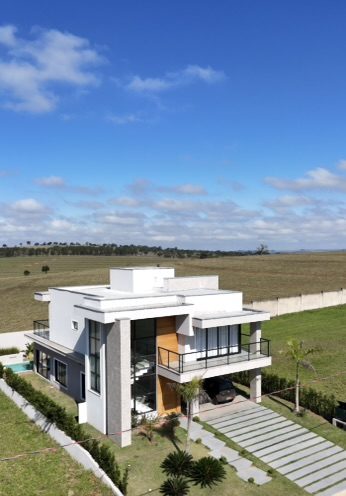 Casa Moderna de Alto Padrão construída pela Construsa: sobrado de dois pavimentos com fachada branca, detalhes em madeira, varanda com guarda-corpo de vidro e piscina