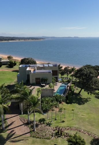 Casa Moderna de Alto Padrão de 459 m² construída pela Construsa no condomínio Riviera Santa Cristina XIII, SP, à beira da represa: dois pavimentos, piscina de borda infinita, paisagismo com palmeiras e praia particular