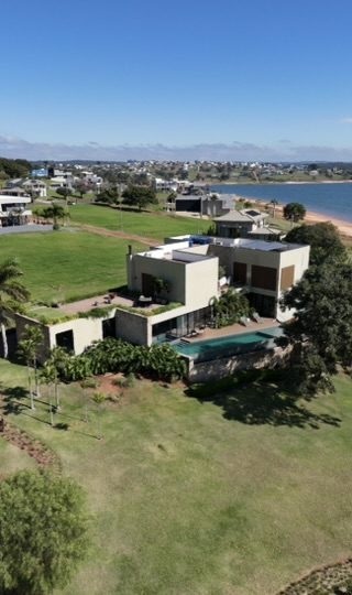 Vista aérea da casa de 459 m² no condomínio Riviera Santa Cristina XIII, à beira da represa, mostrando o terreno gramado, a piscina e o entorno do condomínio