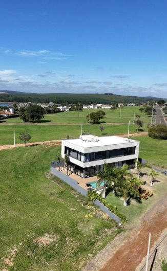 Casa de Campo em Steel Frame de 238 m² construída pela Construsa em Sorocaba, SP: dois pavimentos com fachada branca, amplos vidros, piscina e paisagismo com palmeiras