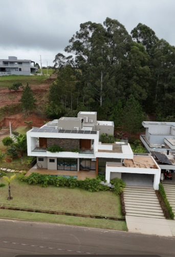 Vista aérea da casa de 238 m² em Sorocaba, mostrando as placas solares no telhado, o jardim no terraço e a garagem