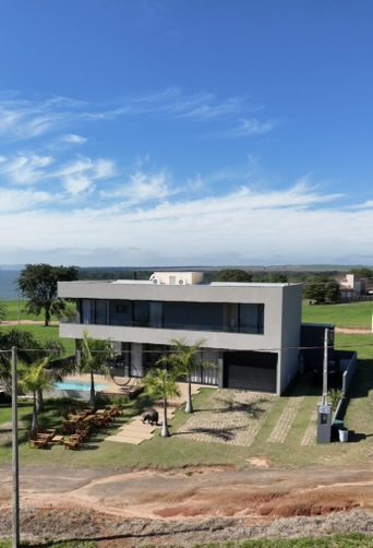 Vista aérea da casa de 259 m² em Steel Frame com piscina, deck de madeira e vista para a represa