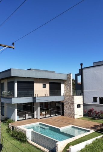 Casa de Campo em Steel Frame de 259 m² construída pela Construsa em São Paulo: fachada em concreto, madeira e pedra, varanda com guarda-corpo de vidro, deck e piscina