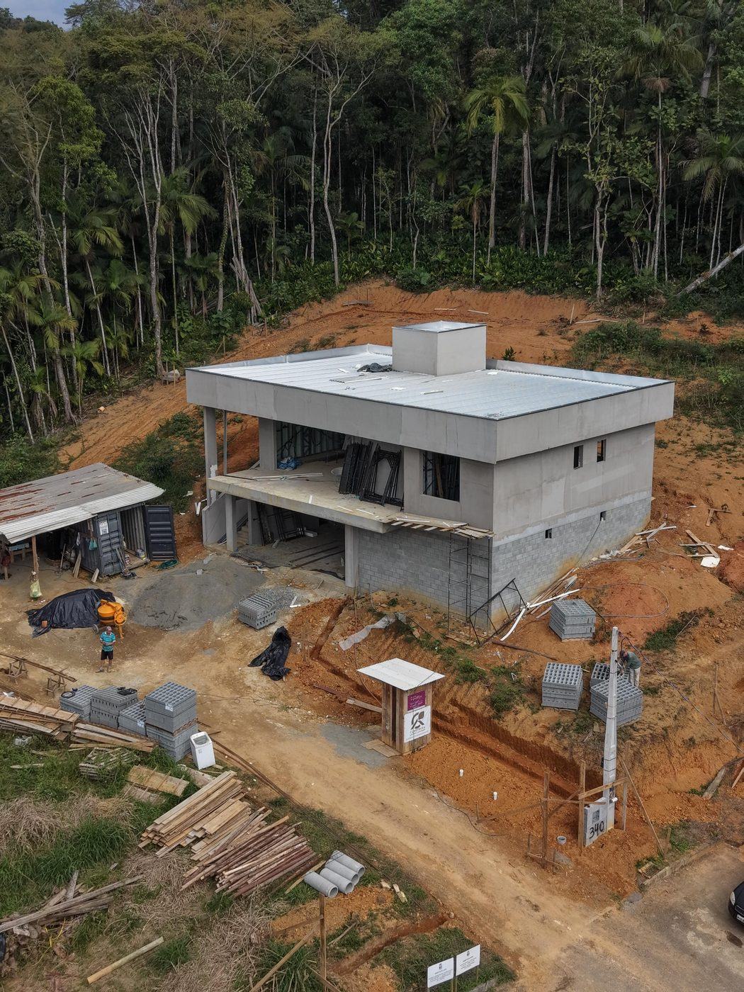 Casa de Campo ZR em execução pela Construsa em Pomerode, SC: residência de dois pavimentos com laje plana, estrutura em concreto e alvenaria, implantada em encosta diante da mata atlântica