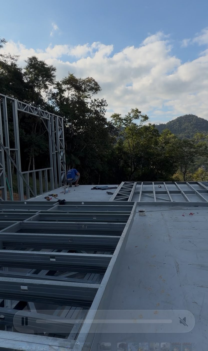Painéis e treliças de aço galvanizado posicionados no terreno da Casa de Campo ZR antes da montagem