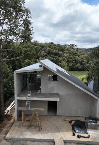 Obra da casa de campo em execução, com a estrutura erguida e o telhado inclinado instalado