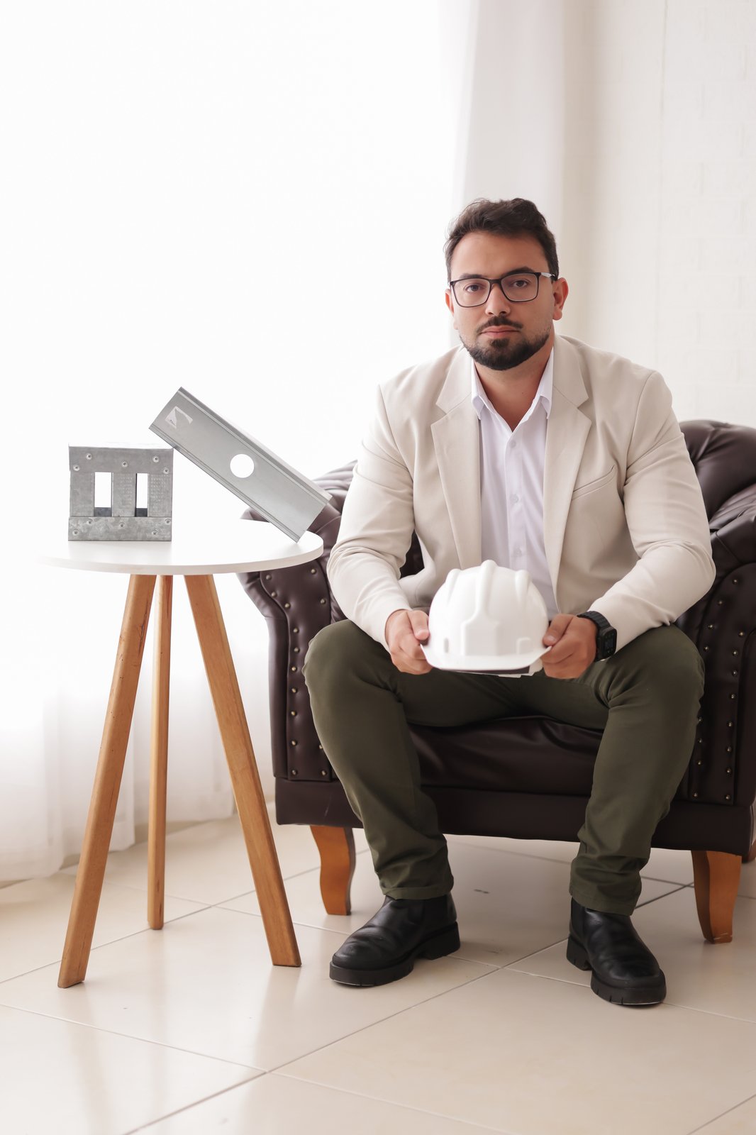 Iago Azevedo, CEO e fundador da Construsa, sentado com um capacete de obra nas mãos ao lado de perfis de aço galvanizado usados em Light Steel Framing